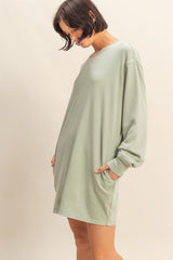 woman wearing a relaxed-fit light green long sleeve dress with side pockets