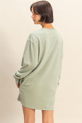 woman wearing a green oversized sweatshirt dress with long sleeves and a relaxed fit, seen from the back