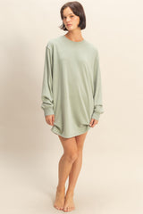 woman wearing a light green oversized long sleeve dress standing barefoot