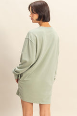woman wearing a green oversized sweatshirt dress with long sleeves and a relaxed fit, seen from the back
