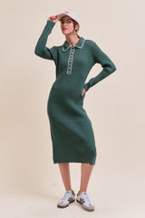 woman wearing a green ribbed midi dress with a collar and button detail, paired with a white cap and sneakers