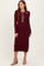 woman wearing a burgundy ribbed long sleeve dress with a collared neckline and button detailing, paired with tan heeled boots