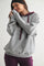 woman wearing a gray oversized hoodie with burgundy drawstrings and matching joggers, smiling and posing against a plain background