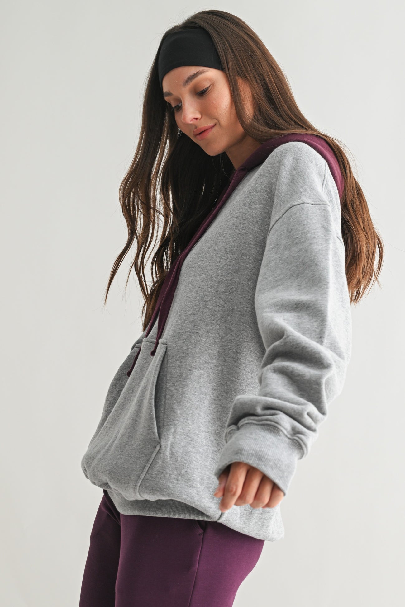 woman wearing a gray and maroon colorblock oversized hoodie with a front pocket and relaxed fit