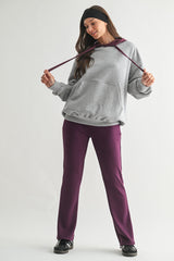 woman wearing a grey oversized hoodie with burgundy drawstrings and purple jogger pants