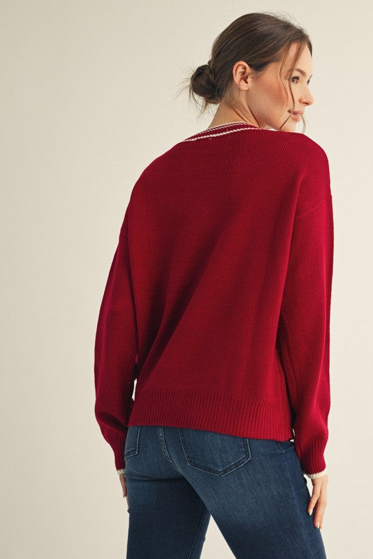 woman wearing a crimson oversized sweater, viewed from the back, paired with dark blue jeans