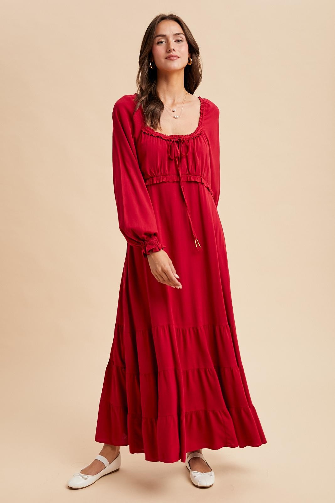 woman wearing a red long sleeve maxi dress with a drawstring neckline and tiered skirt