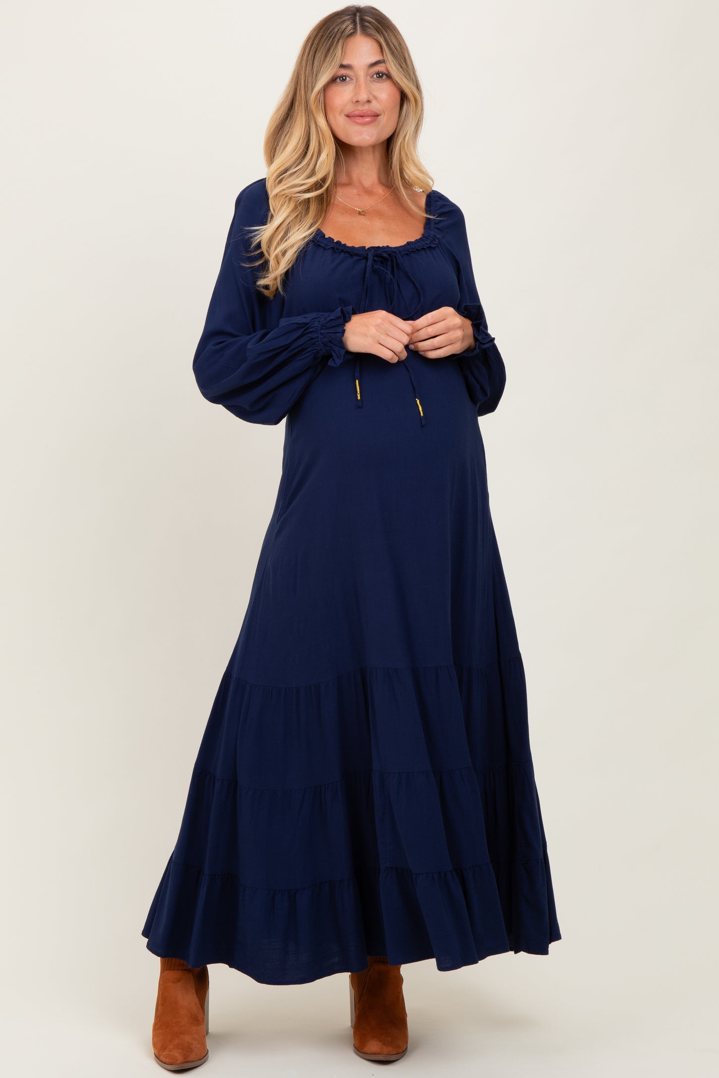 woman wearing a navy blue long sleeve maternity maxi dress with tiered ruffles and adjustable drawstring neckline, showing baby bump