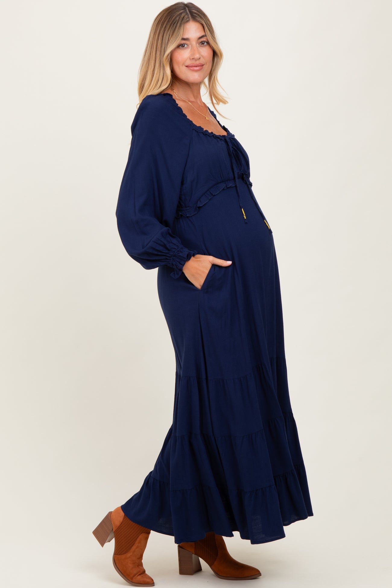 woman wearing a navy blue maternity maxi dress with ruffles and pockets, showing her baby bump