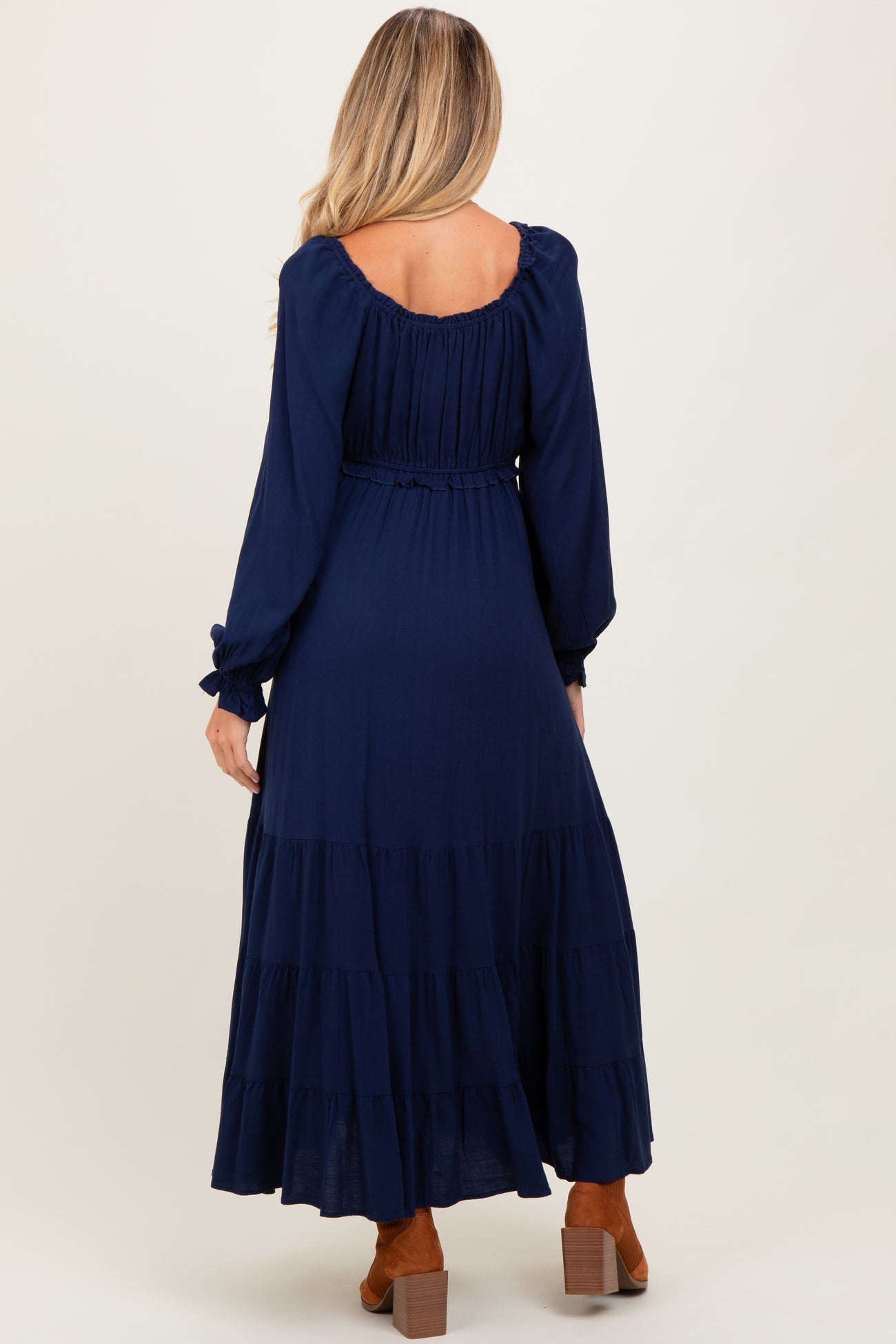 woman wearing a navy blue long sleeve maternity dress with a tiered skirt and elastic waist, showing a baby bump from behind