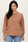 woman wearing a tan ribbed long sleeve sweater with a high neckline and relaxed fit, paired with blue jeans