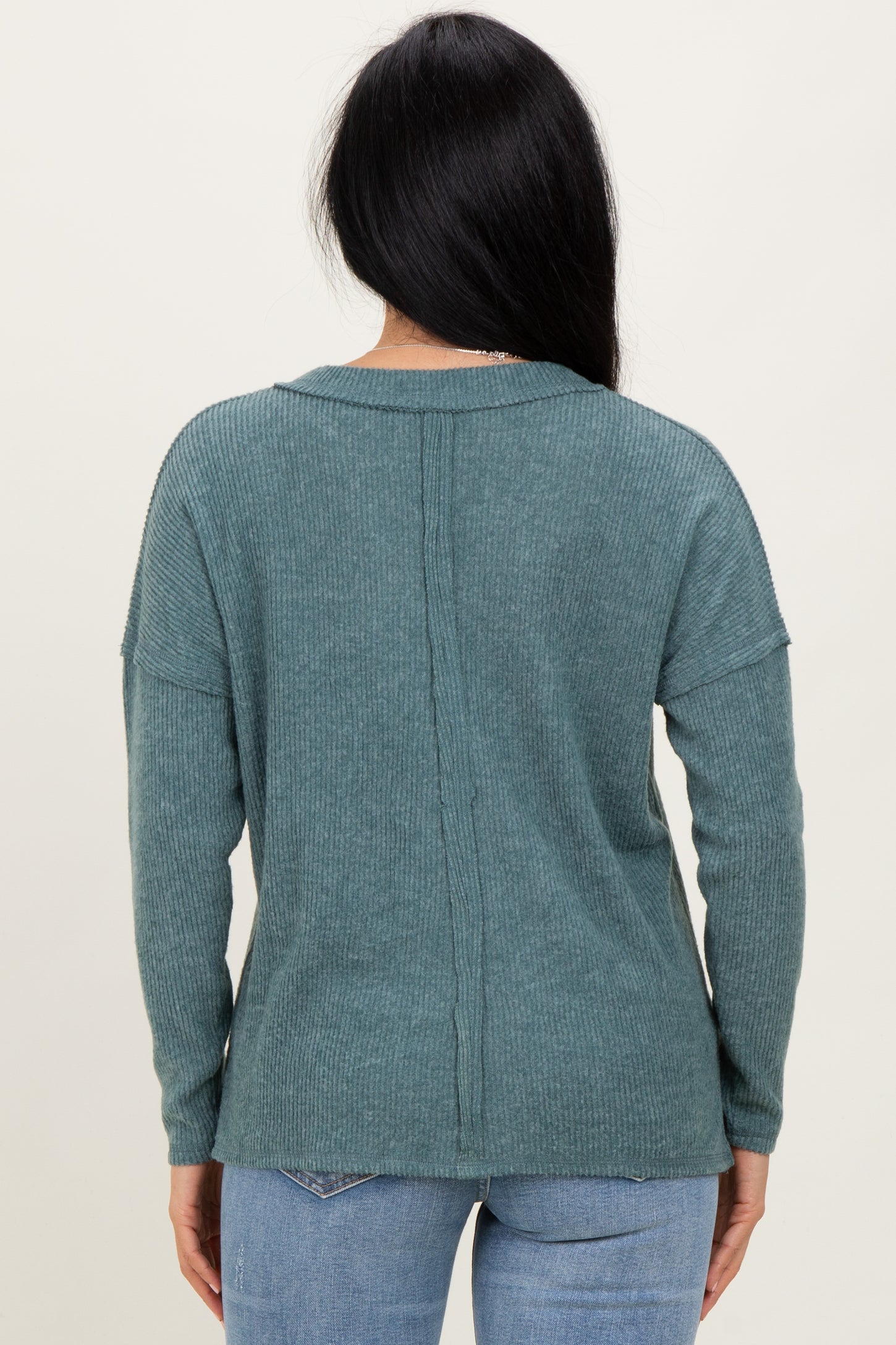 woman wearing a teal ribbed sweater with a relaxed fit and long sleeves, seen from the back