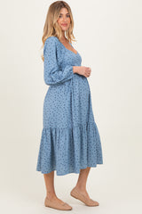 woman wearing a blue polka dot maternity dress with a tiered skirt and a visible baby bump