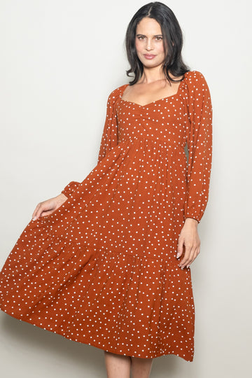 woman wearing an orange polka dot long sleeve midi dress with a square neckline and tiered skirt