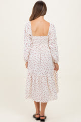 woman wearing a white polka dot maternity dress with a smocked back and long sleeves, showing a relaxed fit