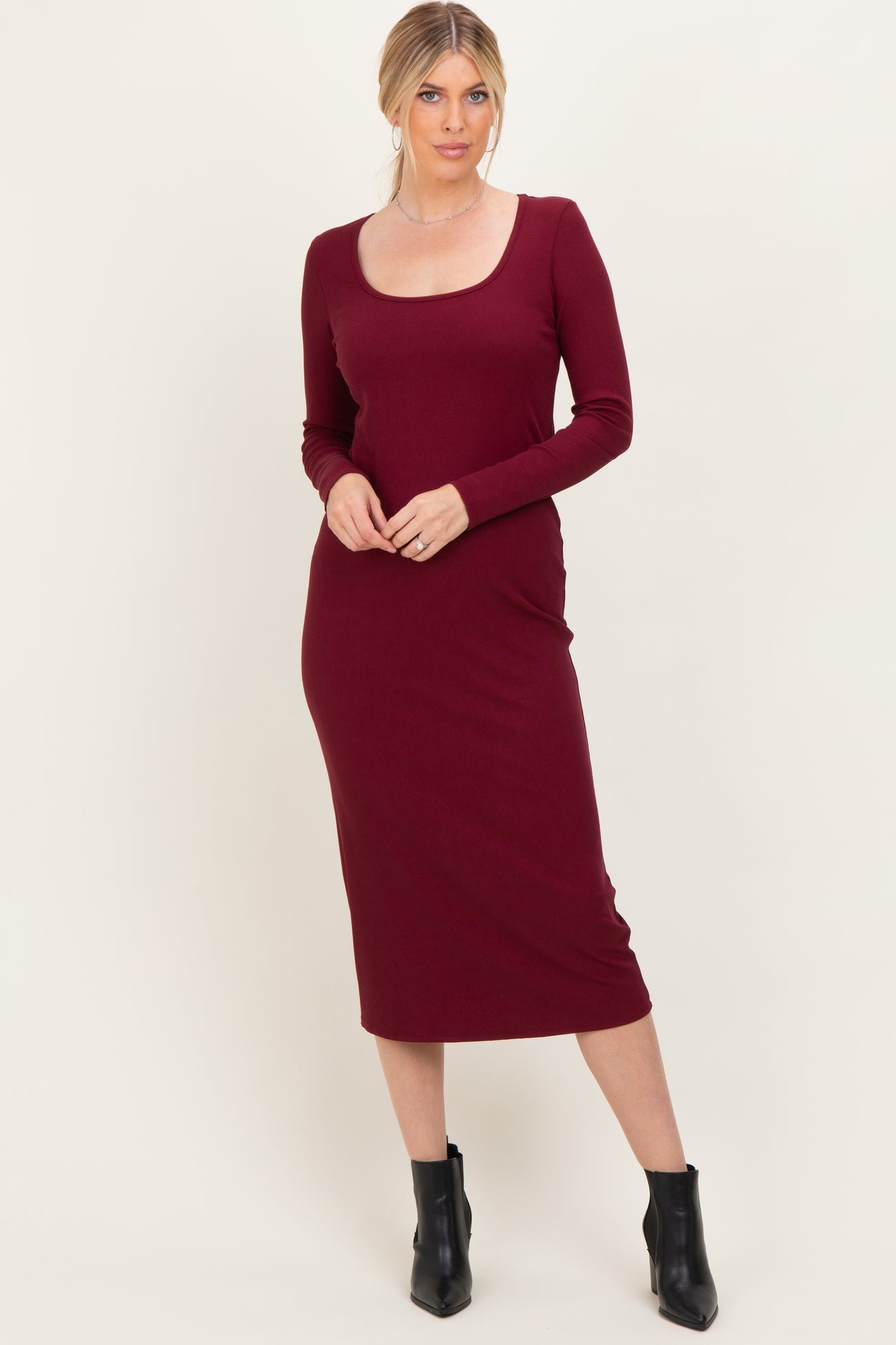 woman wearing a burgundy long sleeve fitted midi dress with a scoop neckline and form-fitting silhouette