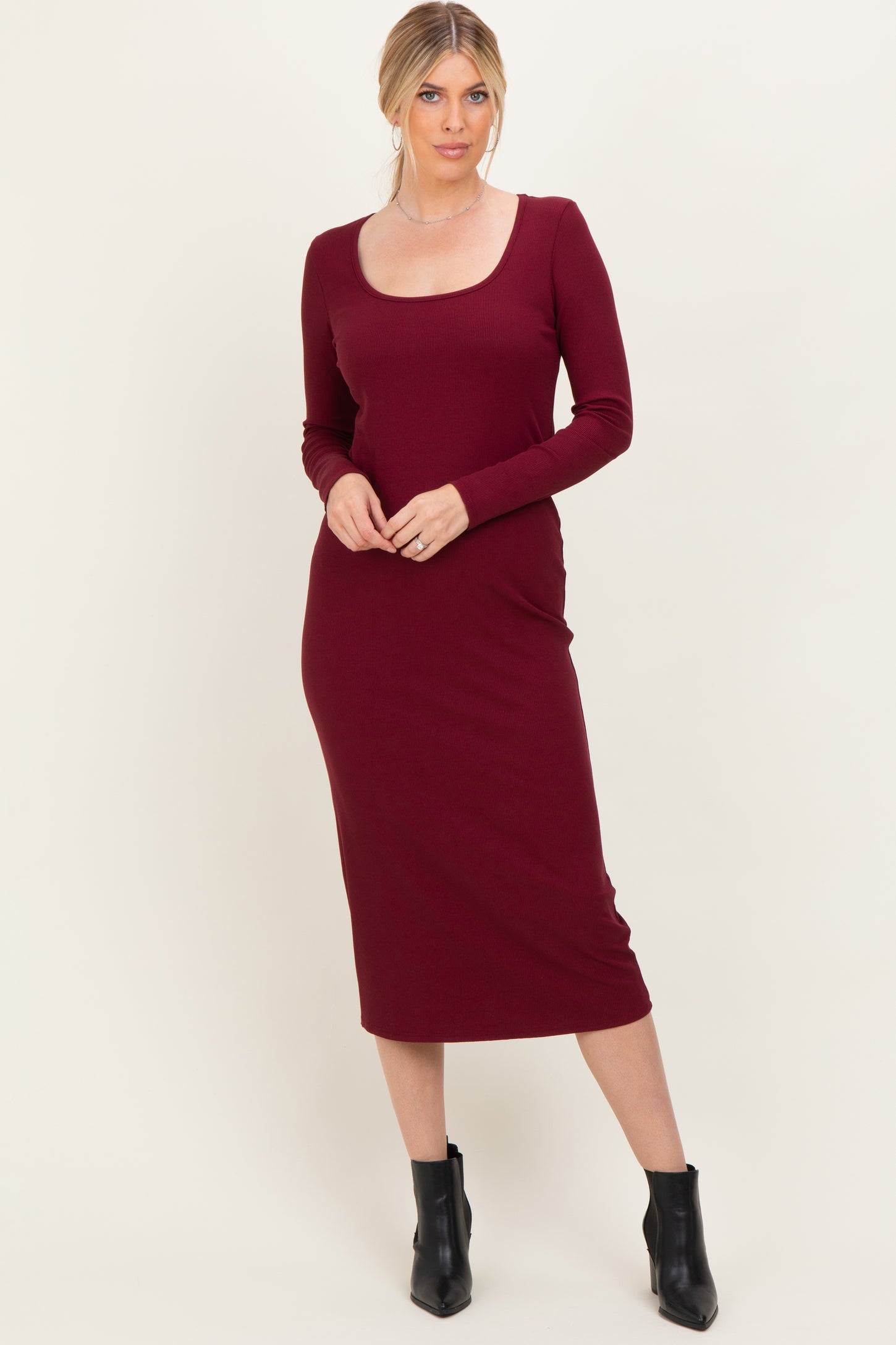 woman wearing a burgundy long sleeve fitted midi dress with a scoop neckline and form-fitting silhouette