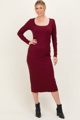 woman wearing a burgundy long sleeve fitted midi dress with a scoop neck and black ankle boots