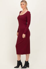 woman wearing a burgundy long sleeve midi dress with a scoop neckline and fitted silhouette