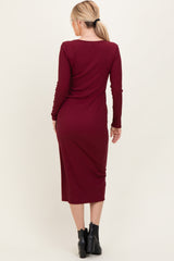 woman wearing a burgundy long sleeve midi dress, viewed from the back, paired with black ankle boots