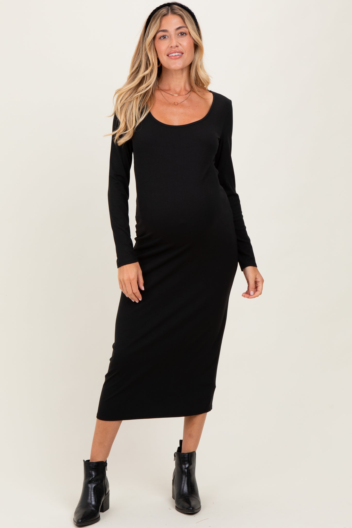 woman wearing a black long sleeve maternity dress with a scoop neckline and baby bump visible