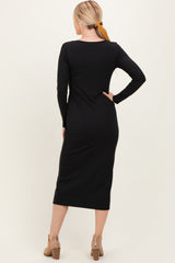 woman wearing a black long sleeve midi dress with a fitted silhouette and side slit, seen from the back