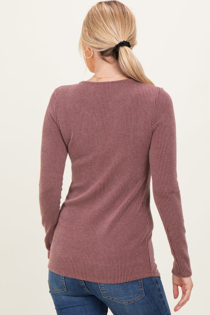 woman wearing a mauve long sleeve ribbed sweater with a fitted style and a slightly longer back hem