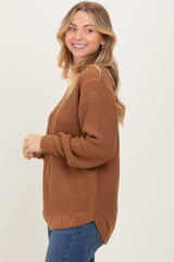 woman wearing a brown waffle knit oversized sweater with side slits and blue jeans