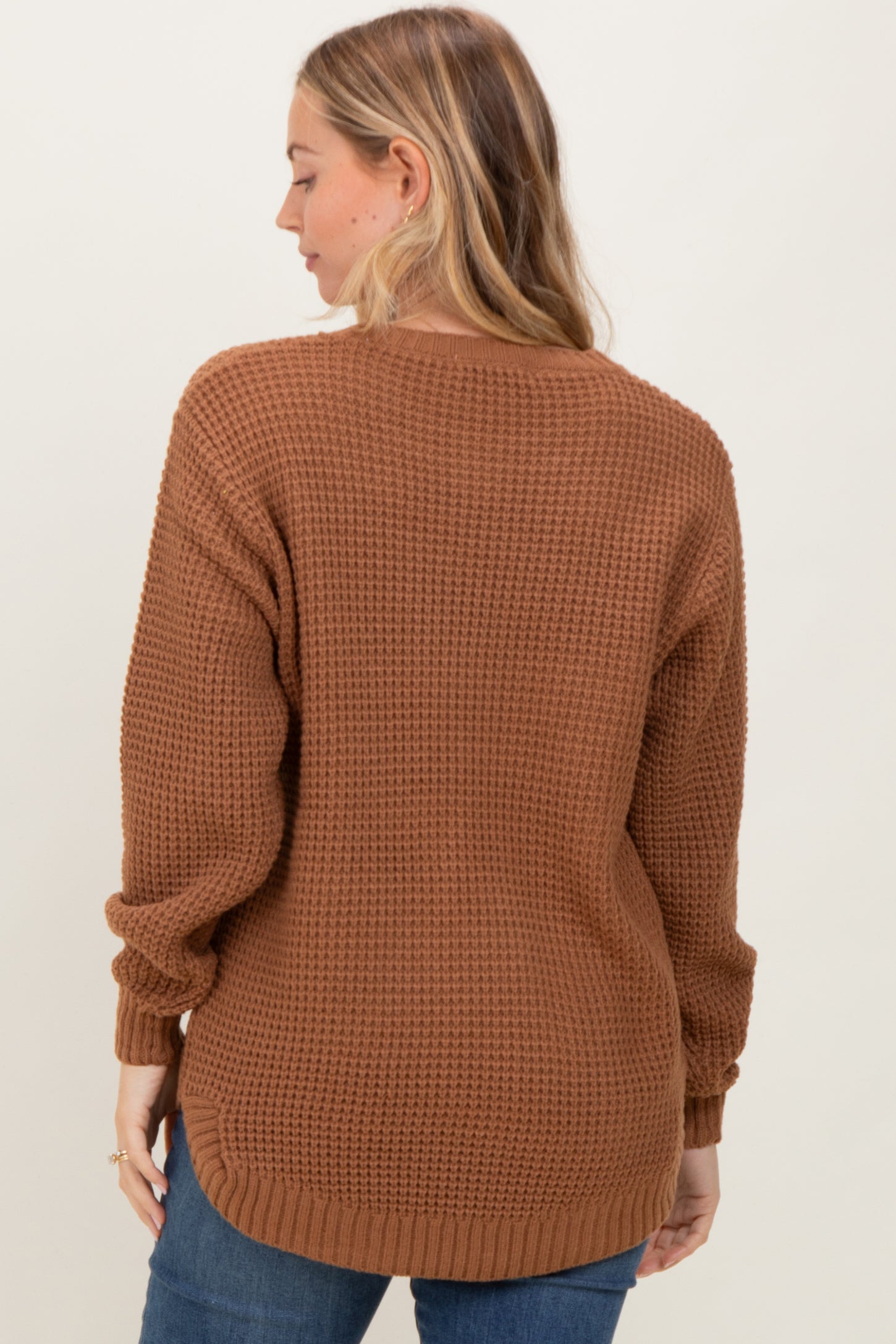 woman wearing a brown chunky knit sweater from the back with relaxed sleeves and a longer hemline