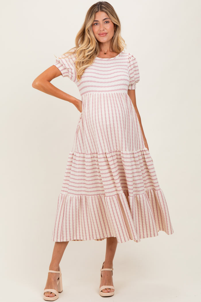 woman wearing a pink and white striped maternity dress with short puff sleeves and a tiered skirt, showing her baby bump
