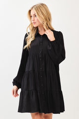 woman wearing a black tiered button-up dress with long puff sleeves and a relaxed fit