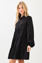 woman wearing a black button-up shirt dress with tiered ruffle details and long sleeves