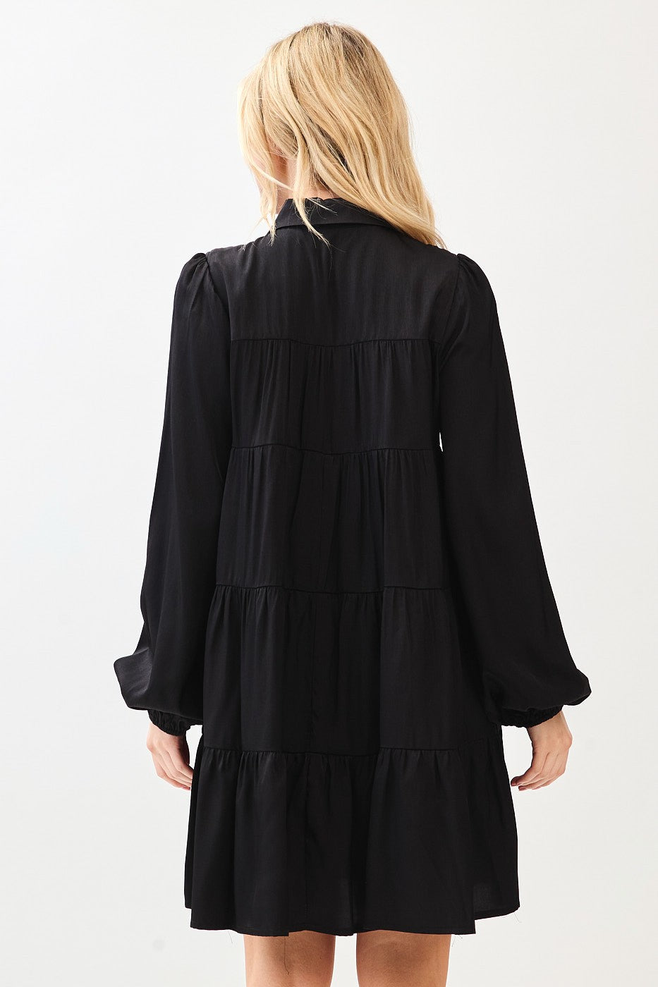 woman wearing a black tiered long sleeve dress with a relaxed fit and gathered details on the sleeves