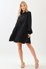 woman wearing a black button-up tiered dress with long sleeves and a flared skirt, paired with beige block-heel sandals