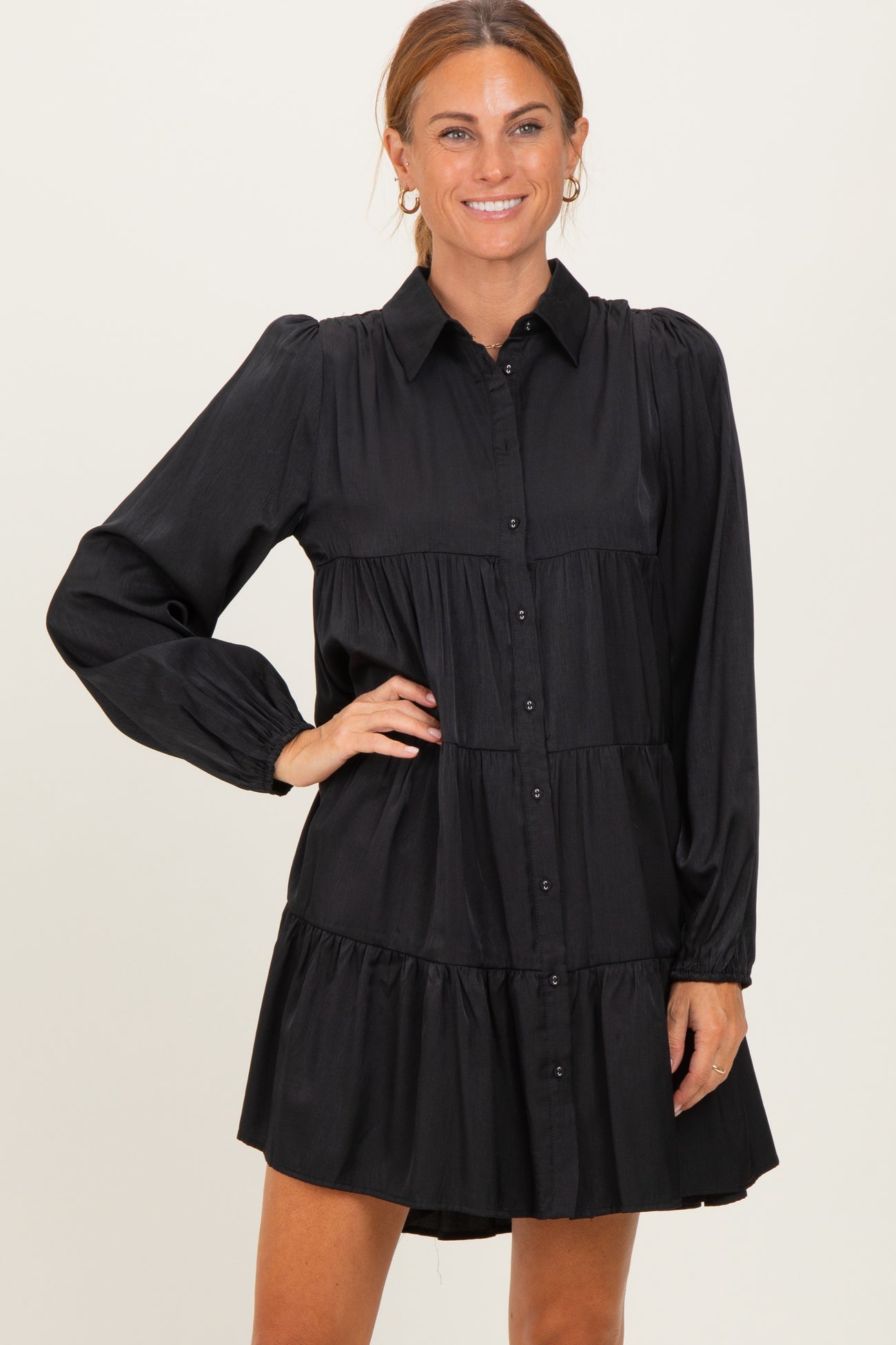 woman wearing a black button-up tiered dress with long sleeves and a collared neck