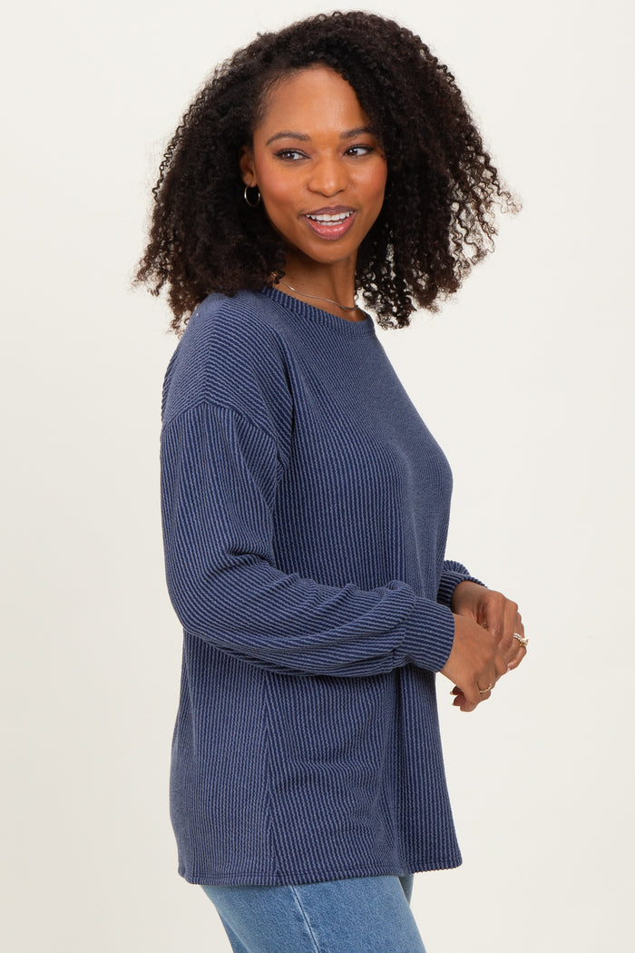 woman wearing a dark blue ribbed knit sweater with long sleeves and relaxed fit, smiling at the camera