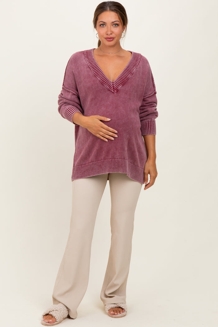 woman wearing a mauve oversized maternity sweater with v-neck and ribbed details, holding her baby bump