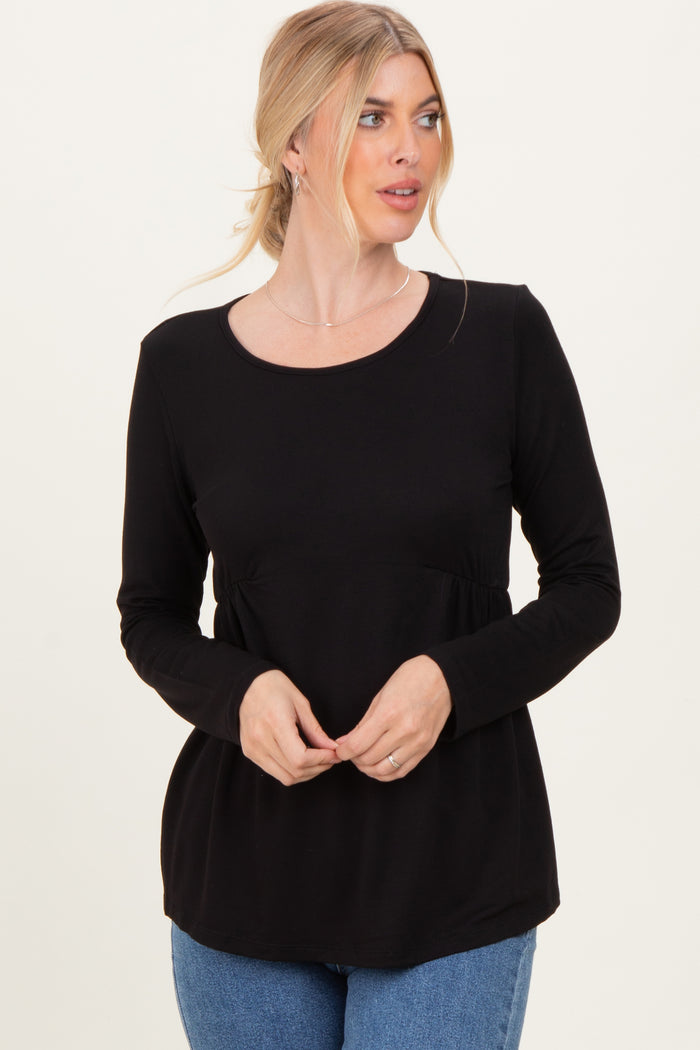 woman wearing a black long sleeve top with a fitted waist and relaxed fit, standing and looking to the side