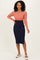 woman wearing a color block ribbed midi dress with a coral top and navy blue bottom, posing with hands on hips