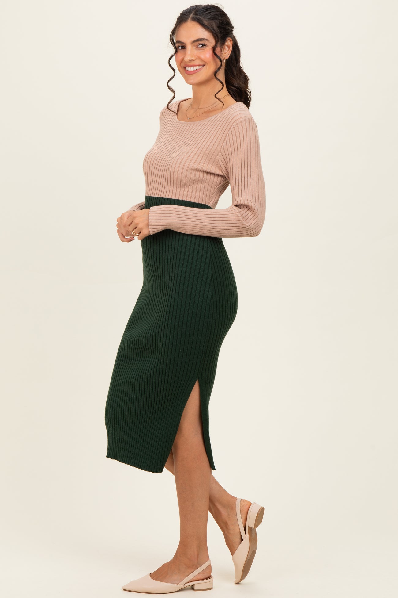 woman wearing a ribbed beige long sleeve top and a dark green midi skirt with a side slit