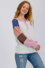 woman wearing a multi-color long sleeve henley top with ribbed sleeves and distressed jeans