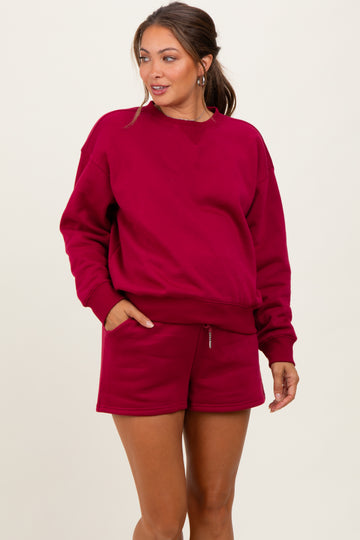 woman wearing a burgundy maternity sweatshirt and matching shorts, showing her baby bump