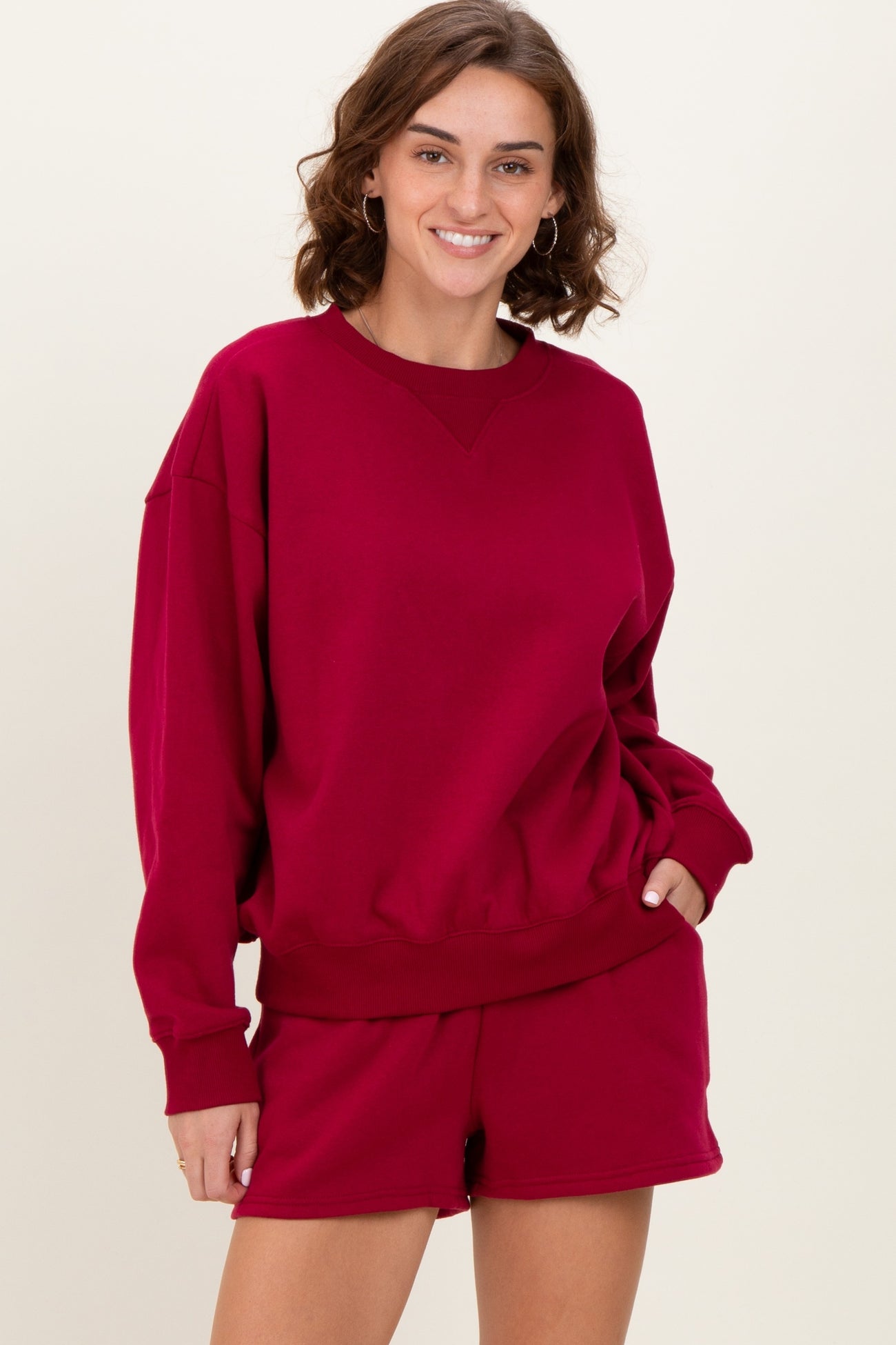 woman wearing a burgundy oversized sweatshirt with long sleeves and matching shorts