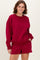 woman wearing a burgundy oversized sweatshirt with long sleeves and matching shorts