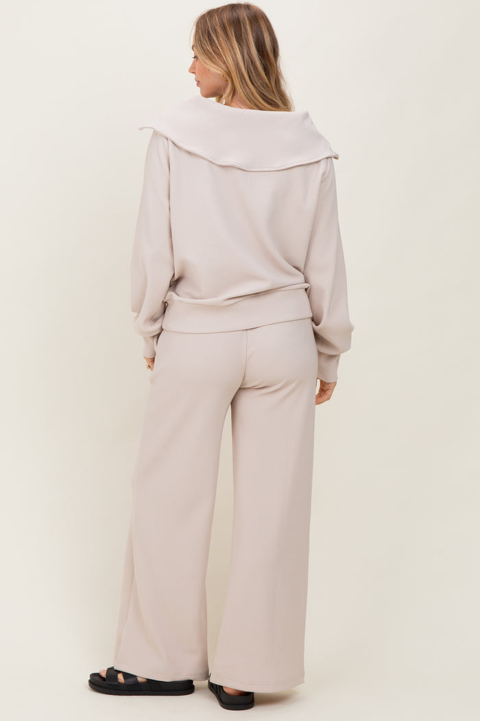woman wearing a light beige oversized ribbed sweater with wide sleeves and matching wide-leg pants
