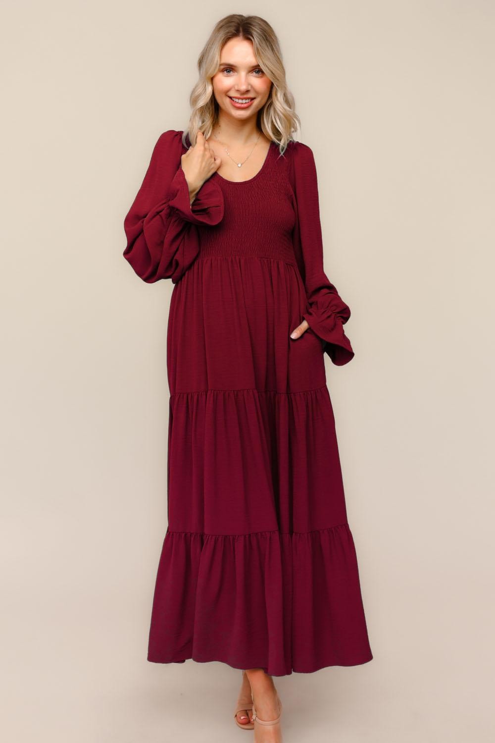 woman wearing a burgundy long sleeve tiered maxi dress with puff sleeves and pockets