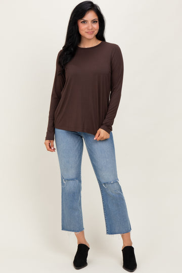 woman wearing a brown long sleeve top with a relaxed fit and distressed light wash jeans