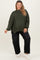 maternity wear in dark green oversized sweater paired with black loose-fitting jeans, model smiling and standing confidently