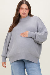 woman wearing a light gray oversized ribbed maternity sweater and holding her baby bump