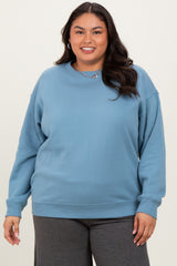woman wearing a light blue oversized sweatshirt with a round neckline and long sleeves, smiling at the camera